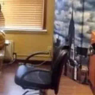 An office space with a chair facing a window and cityscape wall decoration.