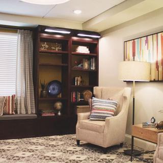 A cozy living room with an armchair, bookshelf, and warm lighting.