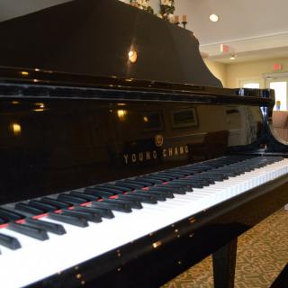 A black grand piano with a glossy finish in a well-lit room.