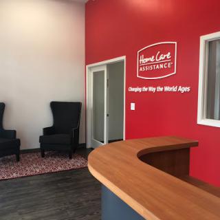 A modern office reception area featuring a wooden desk and comfortable seating against a vibrant red wall.