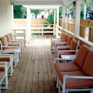 A wooden deck with cushioned chairs arranged neatly along both sides.