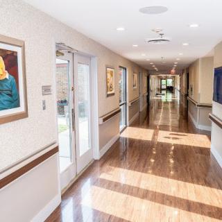A brightly lit hallway with polished floors and artwork on the walls.