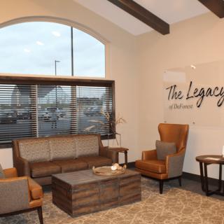 A cozy and modern waiting room with stylish furniture and decor, featuring sofas, chairs, and a large window.