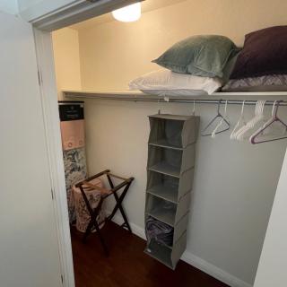 A small closet with shelves, hangers, and a luggage rack for organized storage.