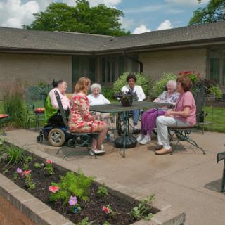 A group of senior citizens enjoying a sunny afternoon together in a garden setting.