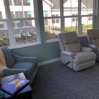 A cozy living room with recliners and a blue armchair near large windows.