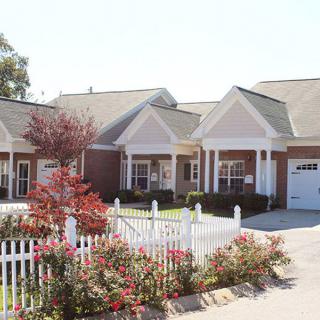 A row of suburban houses with white fences and well-maintained gardens.