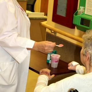 A nurse assisting an elderly patient by feeding them in a healthcare setting.