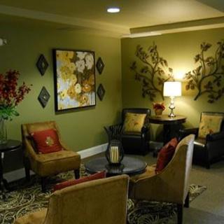 A cozy living room with green walls and elegant decor, featuring comfortable seating and warm lighting.