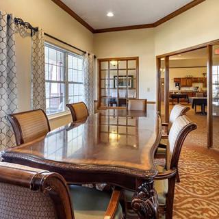 A spacious conference room with a polished wooden table and comfortable chairs, surrounded by large windows letting in natural light.