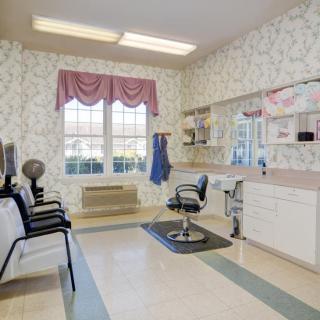 An empty hair salon with a line of chairs, a hair styling station, and large windows letting in natural light.