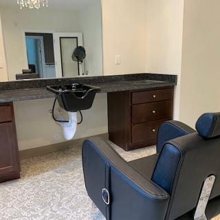 A salon interior featuring a hair washing station with a chair and mirror.