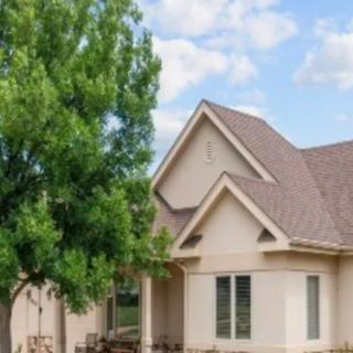A modern suburban house with a gabled roof and a tree in the front yard.