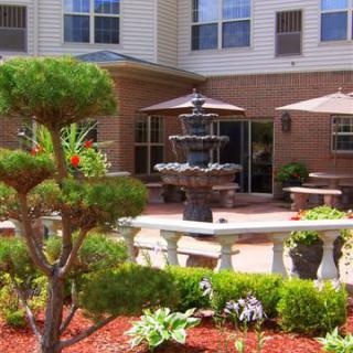 A peaceful garden patio with a central fountain and surrounding greenery.