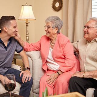 A young man shares a happy moment with his grandparents in the living room.