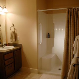 A cozy bathroom featuring a shower with curtains, a sink with a vanity and mirror, and neatly arranged towels.