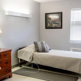 A simple, neatly arranged bedroom with a single bed and wooden dresser.