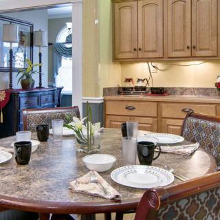 A cozy dining area with a table set for a meal, featuring wooden cabinets and warm lighting.