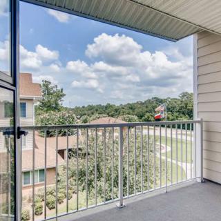 A residential balcony with a view of surrounding buildings and a partly cloudy sky.