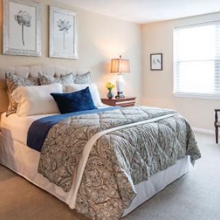 A cozy and stylishly decorated bedroom featuring a comfortable bed, soft linens, and natural light from the window.