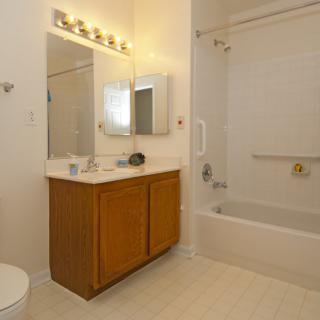 A clean and minimalistic bathroom with a vanity, mirror, lighting, and bathtub.