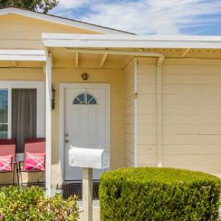 A small house with a porch, featuring a white front door and a mailbox.