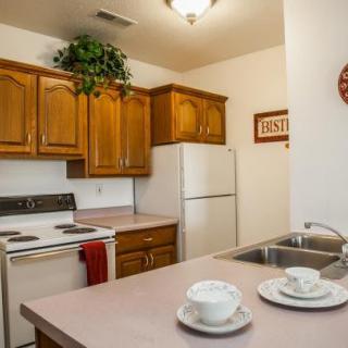 A cozy kitchen with wooden cabinets, a stove, and a refrigerator.
