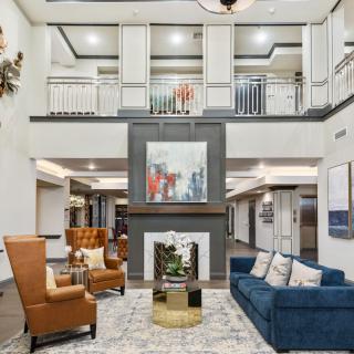 A modern lobby with comfortable seating, a central fireplace, and contemporary artwork.