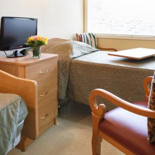 A cozy hospital room featuring two beds, a television, and a nice bouquet of flowers.