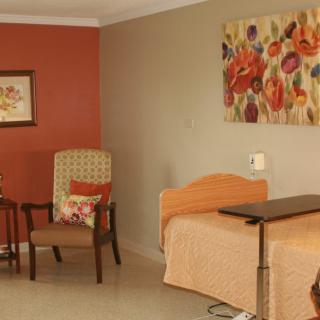 A cozy bedroom with a single bed, chairs, and vibrant artwork on the walls.