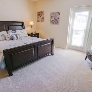 A cozy bedroom with a dark wood bed, bedside lamp, and wall artwork.