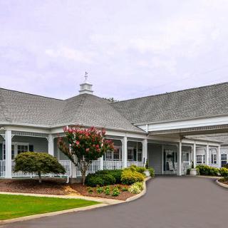 A welcoming building entrance with well-maintained landscaping and a spacious driveway.