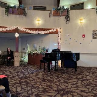 A spacious event venue set up for a musical performance, featuring a grand piano and decorated ambiance.