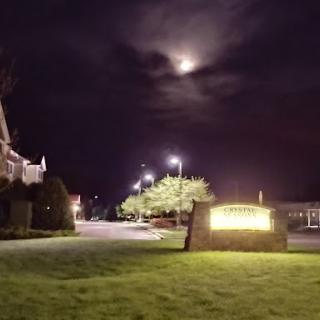 A serene night scene featuring a glowing sign under a partially obscured moon.