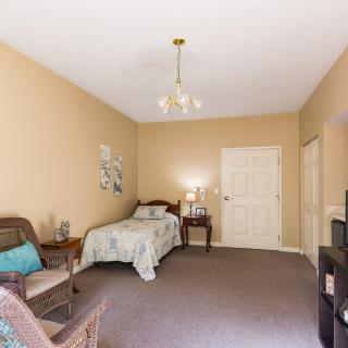 A traditionally decorated bedroom with a single bed, chair, and carpeted floor.