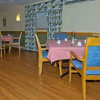 A cozy dining area with tables and chairs arranged neatly on a wooden floor.
