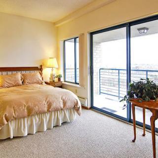 A cozy bedroom with a large bed, lamp, and access to a balcony.