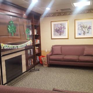 A cozy living room featuring a brown sofa, a fireplace, and decorative artwork on the walls.