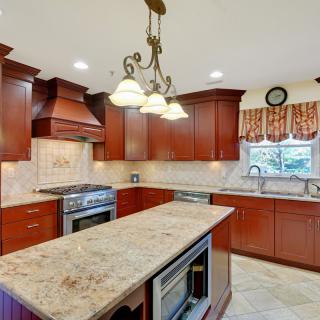 A spacious kitchen with wooden cabinets, a granite island, and modern appliances.