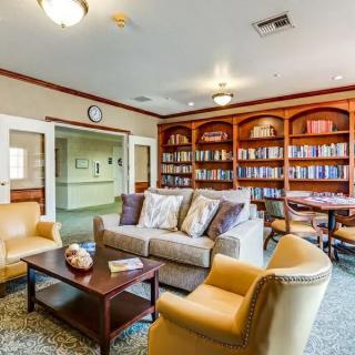 A cozy reading room with bookshelves, comfortable seating, and a coffee table.