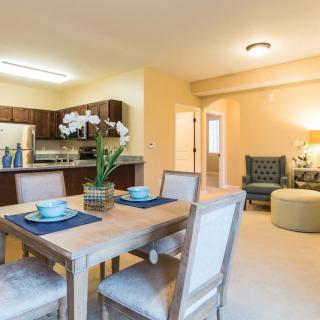 A cozy open floor plan featuring a dining area with a wooden table and a living space with comfortable seating.