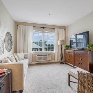 A cozy living room with a sofa, television, and large window with curtains.