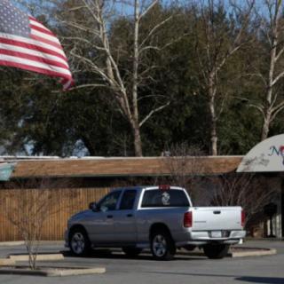 A pickup truck parked in a lot with an American flag nearby.