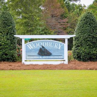 A welcoming sign for a community, surrounded by neatly trimmed bushes and a well-maintained lawn.