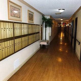 A long hallway with mailboxes lining one side and framed artwork on the walls.