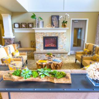 A cozy living room with a fireplace and comfortable seating arrangement, adorned with plants and stylish decor.