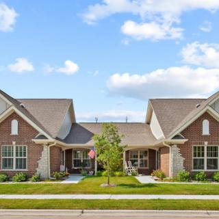 A suburban duplex with a well-maintained lawn under a clear blue sky.