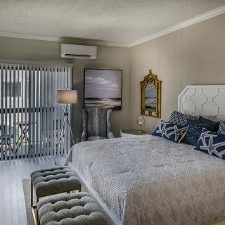 A luxurious and modern bedroom with elegant decor, featuring a cozy bed, decorative pillows, stylish lamp, and a reflective mirror.
