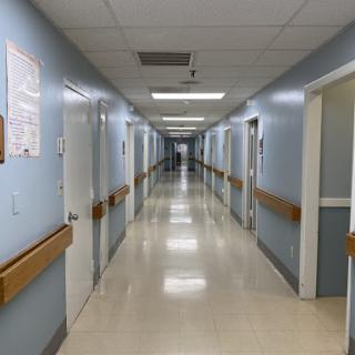 A long, clean corridor in a hospital, featuring blue walls and well-lit spaces.