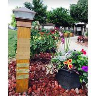 A scenic garden view featuring colorful flowers and a decorative post along a landscaped pathway.